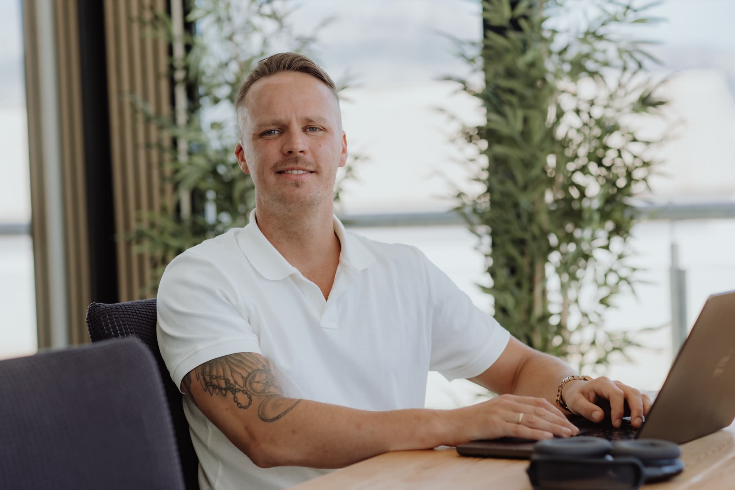 Martin Støland Hansen ved laptopen foran et vindu med utsikt mot sjøen